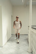 Chico joven tatuado y musculoso posando con ropa de verano en hotel