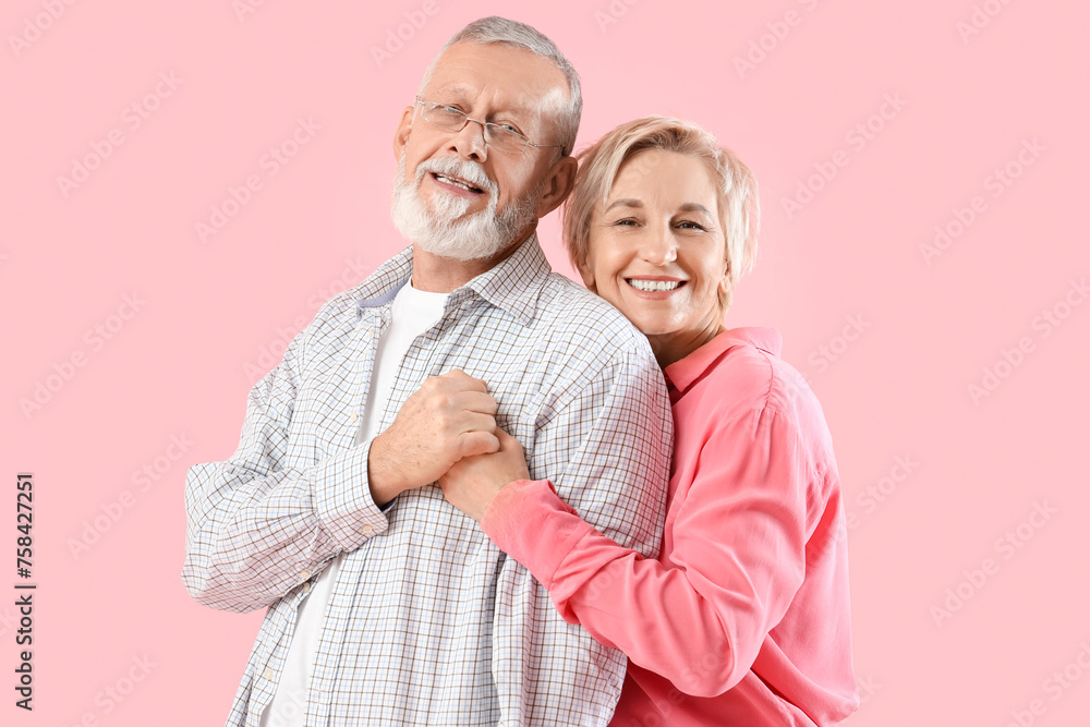 Mature couple hugging on pink background