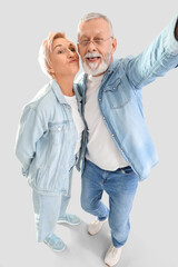 Poster - Mature couple in denim clothes taking selfie on light background