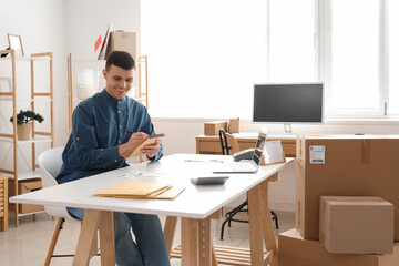 Wall Mural - Male online store seller writing at table in warehouse