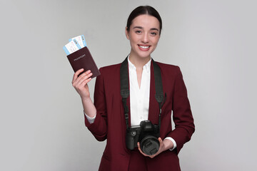 Canvas Print - Smiling businesswoman with passport, tickets and camera on grey background