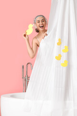 Poster - Young woman in bathtub with paper ducks and curtain on pink background