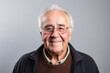 © Igor - Portrait of a smiling senior man with glasses on a gray background
