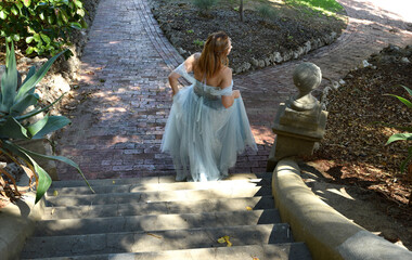 Poster - full length portrait of beautiful female model wearing blue fantasy ballgown, like a fairytale princess. walking around a real stone castle palace location with balconies and staircases.