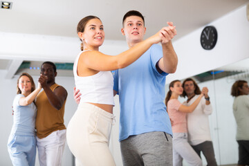 Wall Mural - Woman and man practicing social dance moves in pair during group class