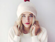 Portrait of a young woman with striking blue eyes wearing a cozy winter hat, exuding a soft and serene look