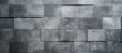 A closeup shot showcasing a rectangular grey tiled wall. The pattern displays symmetry and various tints and shades, creating a sleek flooring design using composite building material