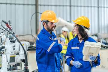 Wall Mural - woman engineer in uniform helmet inspection check control heavy machine robot arm construction installation in industrial factory. technician worker check for repair maintenance electronic operation