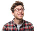 A quirky young man with curly hair and glasses looks up with a quizzical expression on a white background