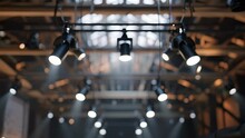 A warehousestyle event venue is illuminated by rows of industrial track lights mounted on exposed wooden beams giving the space an edgy and industrial feel.