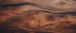 A closeup of a piece of hardwood with a beautiful swirl pattern in brown. The wood stain enhances the natural formation of the trunk, perfect for flooring or plywood