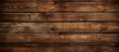 A closeup shot of a brown hardwood plank wall with a blurred background, showcasing the natural wood grain pattern and tints and shades of the wood stain
