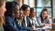 © mister - A diverse group of women sitting around an office table, smiling and engaged in conversation during a work meeting