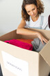 © Wavebreak Media - A young Caucasian woman sorts through a donation box at home