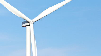 Close-up color photo of large wind turbine blades against a blue sky background with copy space.