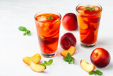 Fototapeta Kuchnia - Peach ice tea in a glass with mint on a white wooden table(selective focus).