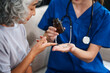 © NanSan - Caucasian female doctor introduces medicine to an elderly Asian patient while seated on a sofa, providing guidance and information about the prescribed medication.