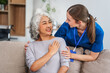© NanSan - A Caucasian female doctor provides encouragement and advice on maintaining good health to an elderly Asian patient while they sit together on the sofa.