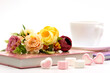 Tea, flowers and sweet hearts on a white background. A cup of tea, dessert in the form of marshmallows, notebooks for a romantic mood.