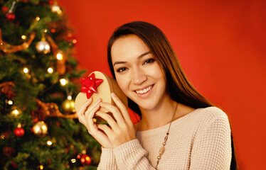 Canvas Print - Portrait, smile and Christmas with woman, gift box and package on a red studio background. Face, person and girl with Xmas parcel and present with surprise and guessing with giveaway prize or holiday