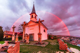 The Chapel of Saint Thomas Becket in Szent Tamas lighten by a strong sunlight with a rainbow behind in rainy clouds in Esztergom, Hungary.