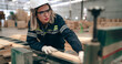 © Nassorn - Confident female engineer working in lumber warehouse of hardwood furniture factory inspecting production machine. Serious female technician, carpenter busy working with tool in woodwork manufacturing