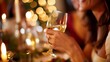 © mirifadapt - Woman holding a glass of wine at a dinner party, Focus on wine glass