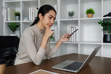 Wall Mural - business woman using smartphone while working on laptop, synchronize data between computer and gadget at home, use corporate devices and business application