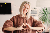 Fototapeta Zwierzęta - Smiling Middle-aged Woman makes a Heart Sign with her hands