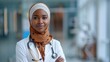 © Soudagar - Over a fuzzy hospital backdrop, a certain of herself African Muslim lady doctor wears a vivid headscarf and space, Generative AI.