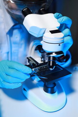 a talented scientist sits in his lab while using a microscope to look for microscopic organisms in a