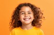Portrait of a cute little girl with curly hair on orange background