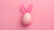 A pink Easter egg with bunny ears on a pink background. Easter design concept with copy space