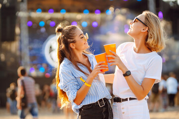 Wall Mural - Two young woman with beer at beach party. Music festival. Summer holiday, vacation concept.