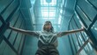 Kobieta o rozpostartych ramionach stoi w wąskim korytarzu więziennym, zamykając drzwi z kratami. Mroczna scena braku wolności.
