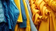 A variety of yellow and blue jackets hanging on a rack. Perfect for fashion or retail concepts