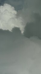 Wall Mural - Flying through beautiful white fluffy clouds in blue sky. Airplane travel background. Vertical video