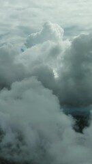 Wall Mural - Flying through beautiful white fluffy clouds in blue sky. Airplane travel background. Vertical video