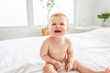 © Louis-Paul Photo - Baby boy in diaper on white sunny bedroom. one years child relaxing in bed.