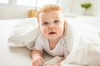 © Louis-Photo - Baby boy in white sunny bedroom. one years child relaxing in bed.