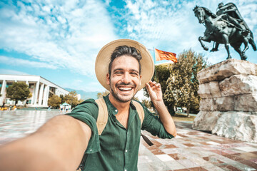 Wall Mural - Happy tourist taking selfie at Skanderbeg square in Tirana, Albania - Smiling handsome young man laughing at camera outside - Summer vacation and European holidays concept