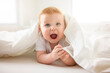 © Louis-Photo - Baby boy in white sunny bedroom. one years child relaxing in bed.