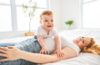 © Louis-Photo - Mother and baby boy on bed, having great moment together on white bedroom