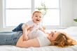 © Louis-Photo - Mother and baby boy on bed, having great moment together on white bedroom