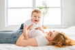 © Louis-Photo - Mother and baby boy on bed, having great moment together on white bedroom