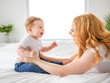 © Louis-Photo - Mother and baby boy on bed, having great moment together on white bedroom