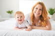 © Louis-Photo - Mother and baby boy on bed, having great moment together on white bedroom