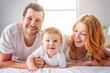 © Louis-Photo - Mother father and baby boy on bed, having great moment together on white bedroom