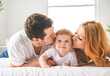 © Louis-Photo - Mother father and baby boy on bed, having great moment together on white bedroom