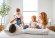 © Louis-Photo - happy family mother, father and children having fun in bed in bedroom at home